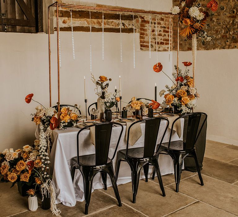 Intimate wedding reception table with copper frame installation and handing light decor 