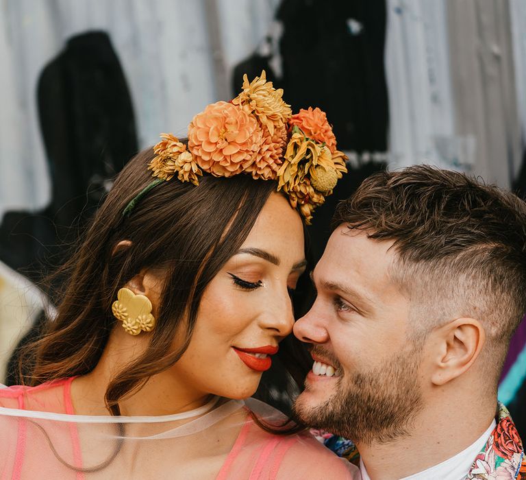 Beautiful bride with winged eyeliner and red lipstick looking at her groom 