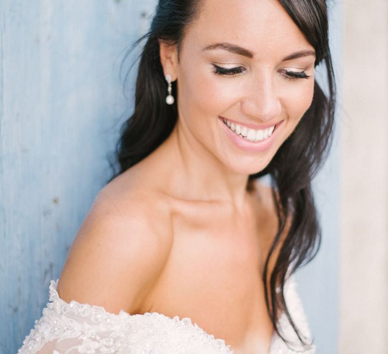 Smiley brunette bride with half up half down wedding hair with drop earrings and natural wedding makeup 