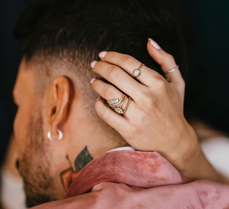 Bride with a wedding band and engagement ring stack embracing her grooms head 