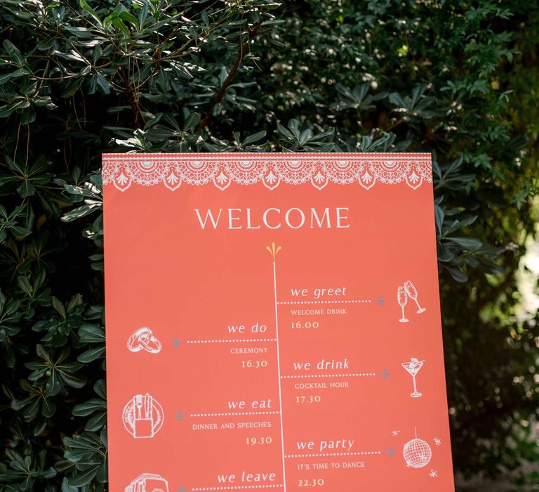 Bright orange personalised welcome wedding stationery stands on wooden easel 