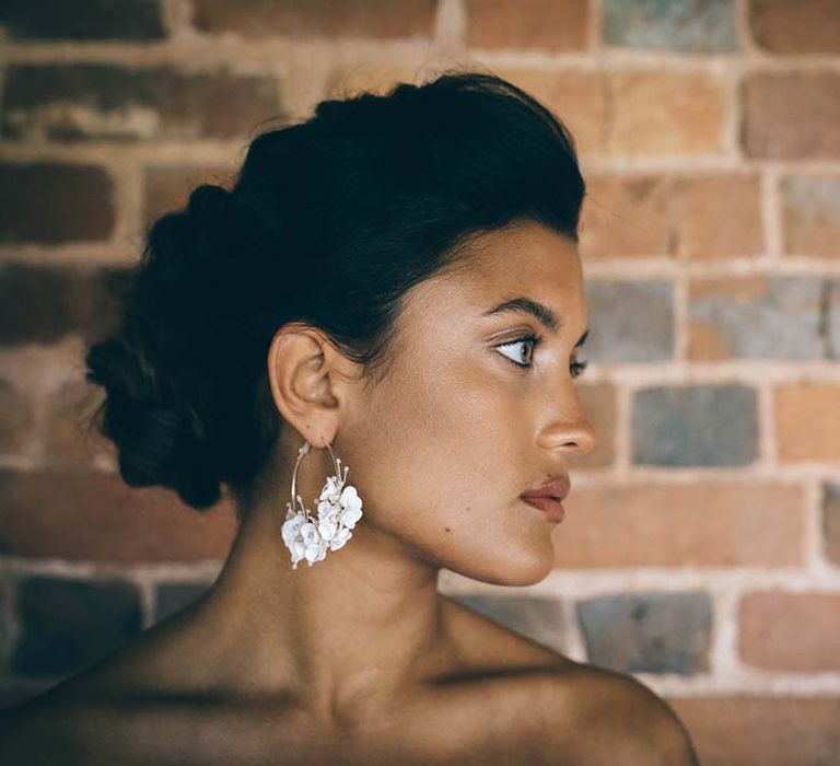 Beautiful bride with a pinned bridal up do wearing flower hoop earrings 