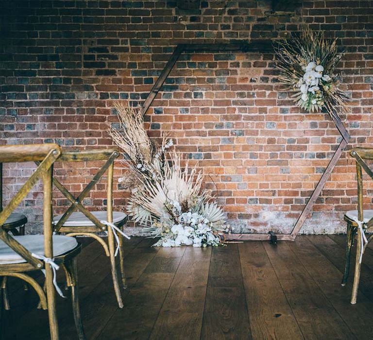 boho black tie wedding ceremony at Brickhouse Vineyard with wooden chairs and hexagonal altar decorated with dried flowers 