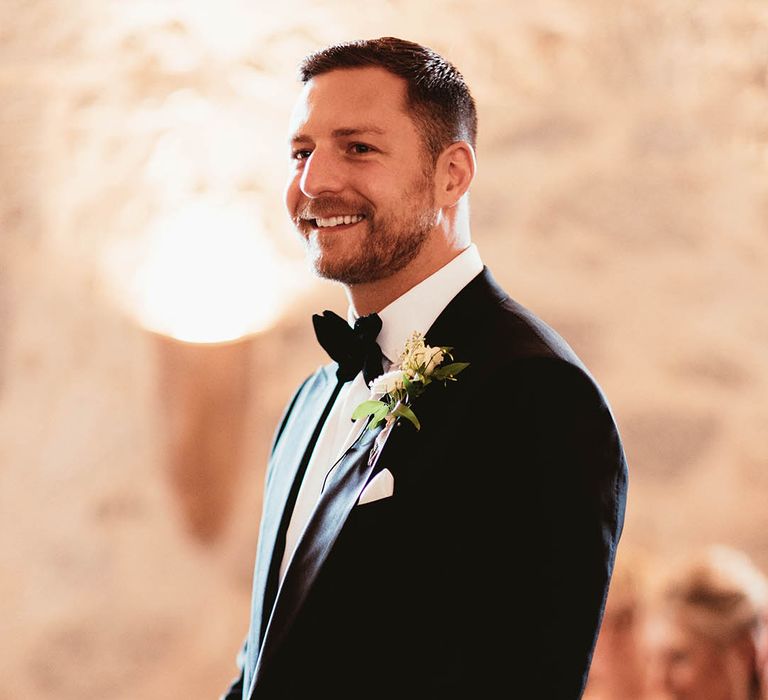 Grooms wears black tie as he awaits his bride on the day of his wedding during ceremony