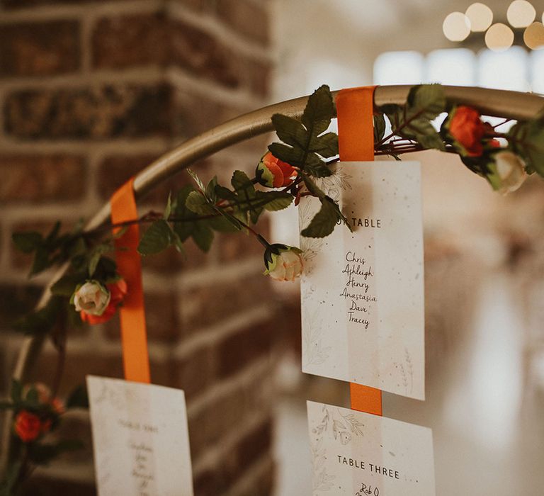 Gold hoop wedding table seating plan with orange ribbon