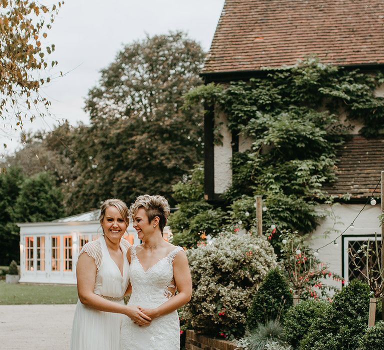 Brides hold hands and walk down pathway on their wedding day