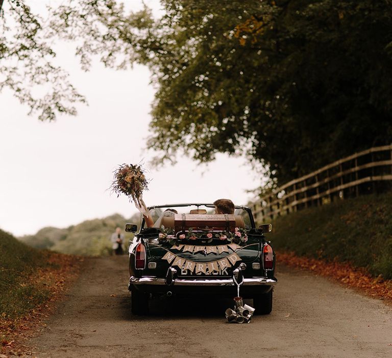 Bride and groom drive off in vintage wedding car 