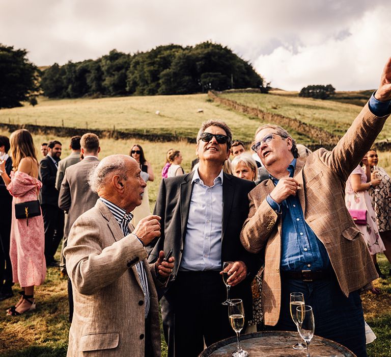 Wedding guests stand outdoors before ceremony