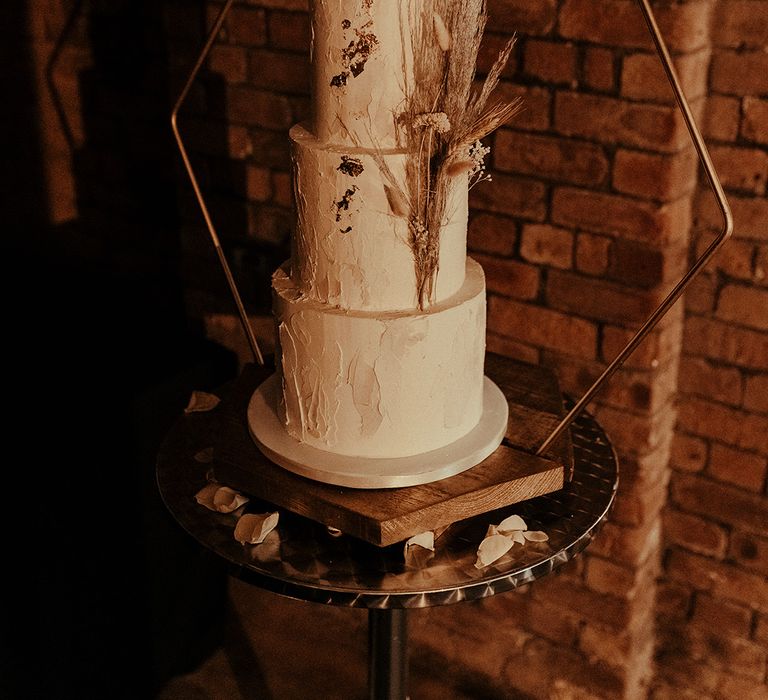 Three tier wedding cake with wire cake topper and hexagon cake stand decorated with dried flowers 