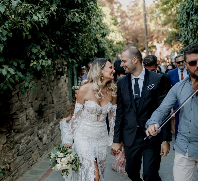 Bride looks lovingly at her groom on their wedding day as they walk hand in hand 