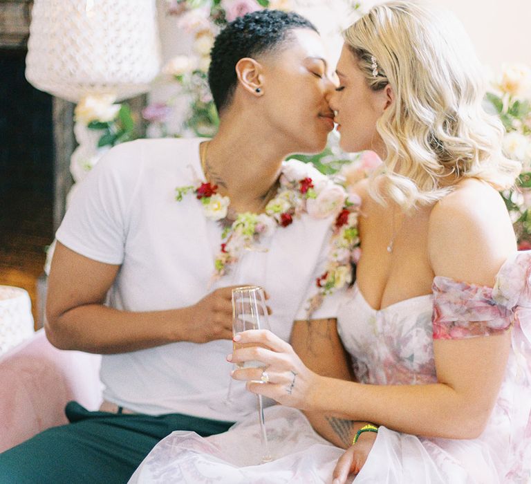 bride in a pink floral princess wedding dress kissing her partner in a white t-shirt and flower collar 