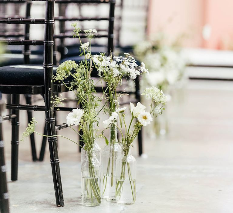 Dark wooden chairs for wedding ceremony with white flower decoration along the aisle