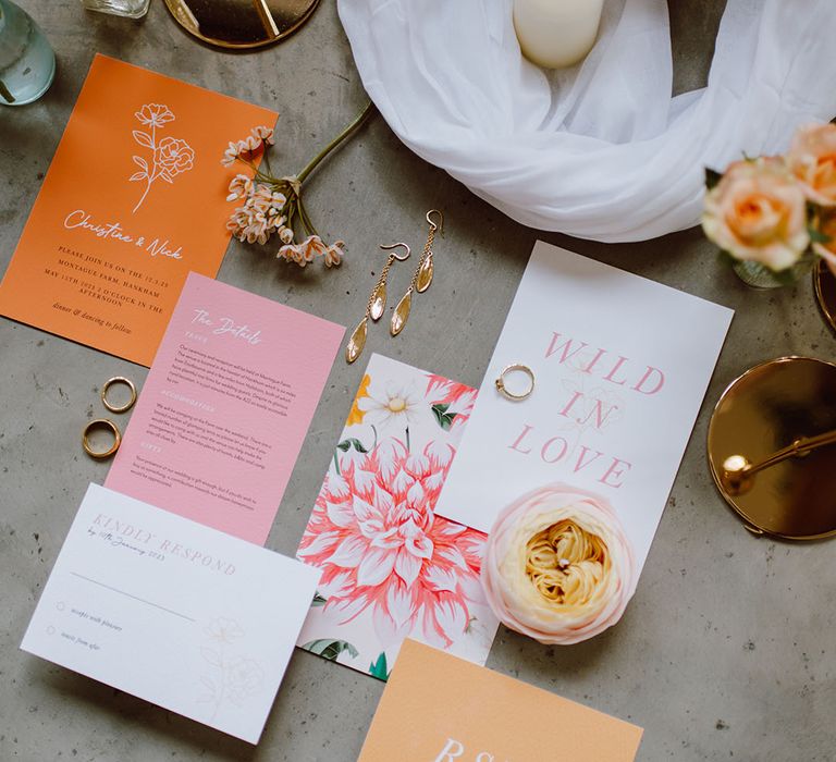 Flatlay of pastel pink, yellow and orange wedding stationery designs 