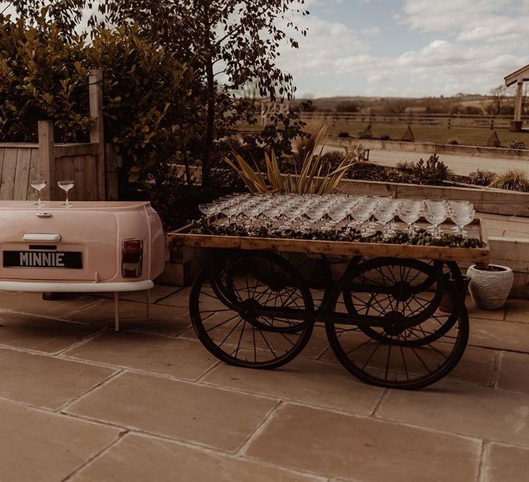 Mini bar made to look like a pink car with cart of cocktail glasses for wedding guests