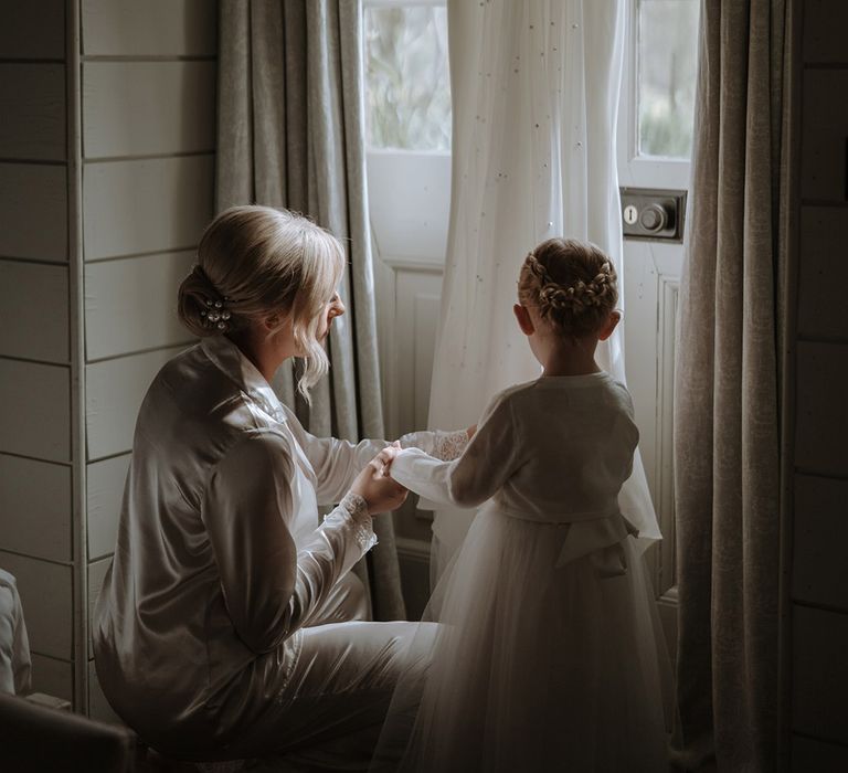 Bride and daughter look at her wedding dress and pearl veil 