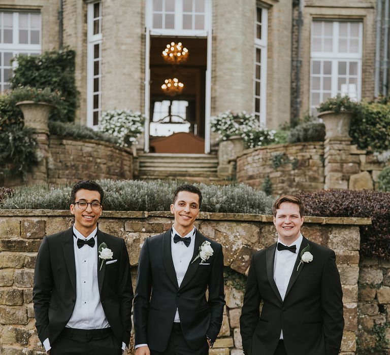 Groom with groomsmen in matching black tie outfits for wedding 