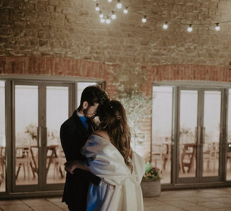 Bride and groom share an embrace outside at the end of their wedding day