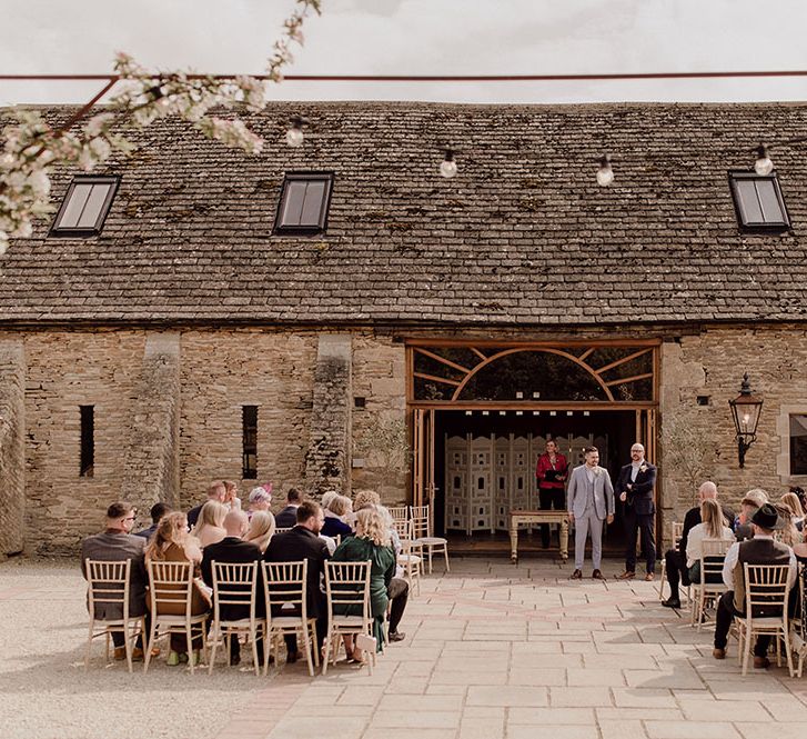 Oxleaze Barn outdoor wedding complete with festoon lighting and wooden chairs 