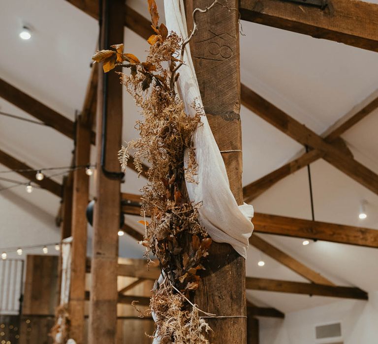 Dried autumnal grasses and leaves hanging with white wedding drapery 