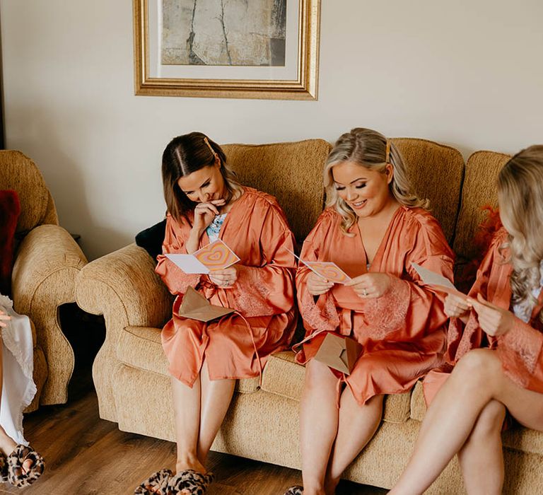 Bridesmaids in orange satin robes read special messages from the bride 