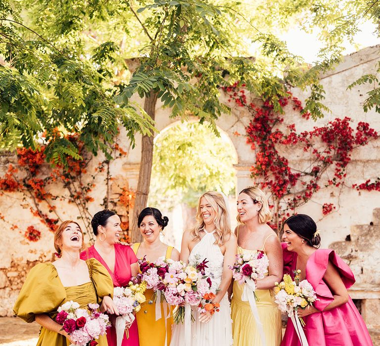 Bride in a flower halter neck wedding dress with her bridesmaids in statement bright pink and yellow dresses