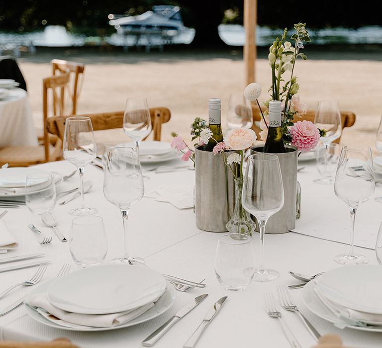 Classic tablescape complete with pastel florals in metal vases on rounded tables for outdoor reception