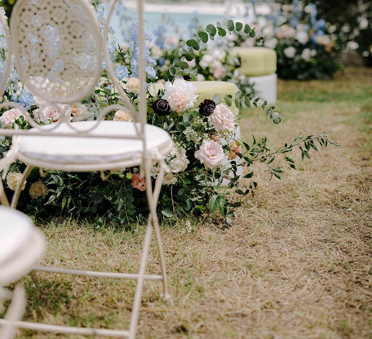 Intricate cream chair surrounded by eucalyptus, roses, thistle and wildflowers