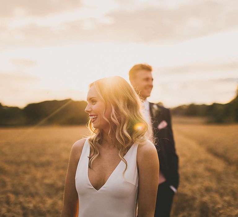 Bride stands in front of Groom during golden hour wedding photography