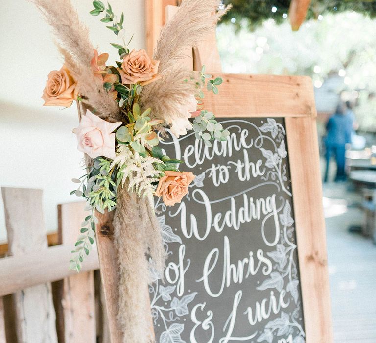 Chalkboard with wooden frame and dried floral decor to the side 