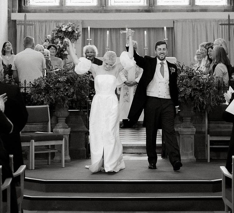 Bride in Jesus Peiro wedding dress celebrates with her groom after church wedding ceremony in Salcombe