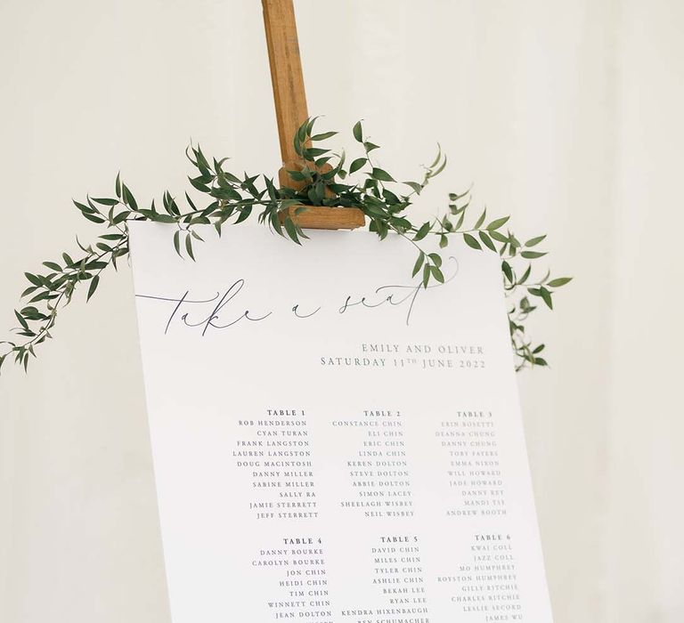 classic wedding table plan sign with green foliage on a wooden easel 