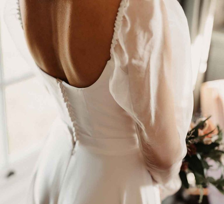 Bride in square neck puff sleeve wedding dress with button detailing on the back 