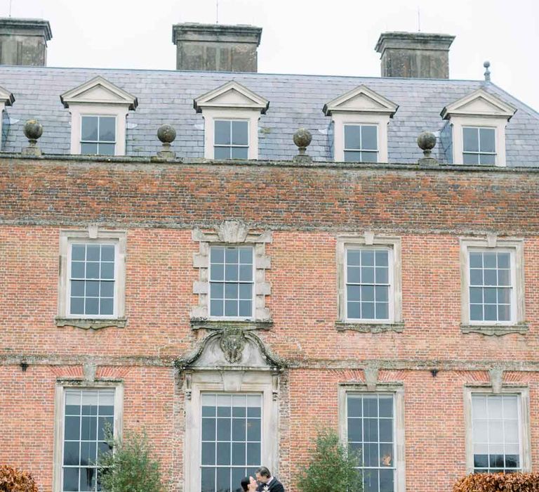 Bride and groom embracing outside of St Giles House country house wedding venue UK 