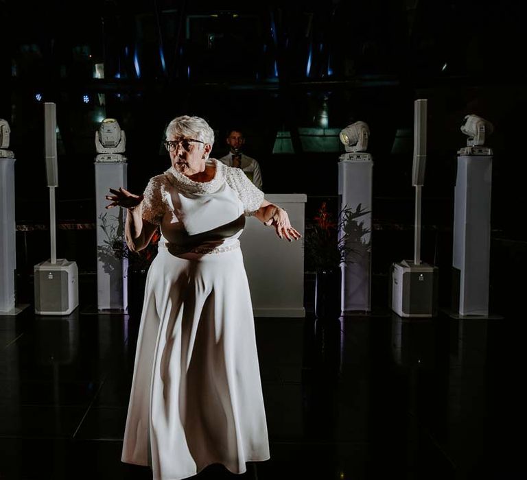 Wedding guest in short sleeve ivory dress with pearl collar and sleeves dancing at The Gherkin wedding venue 