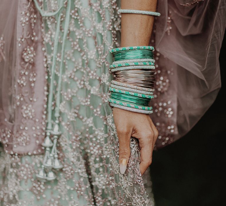 Bride wearing mint green and dusky pink ombre wedding lehenga with embellishments and matching wedding bangles 