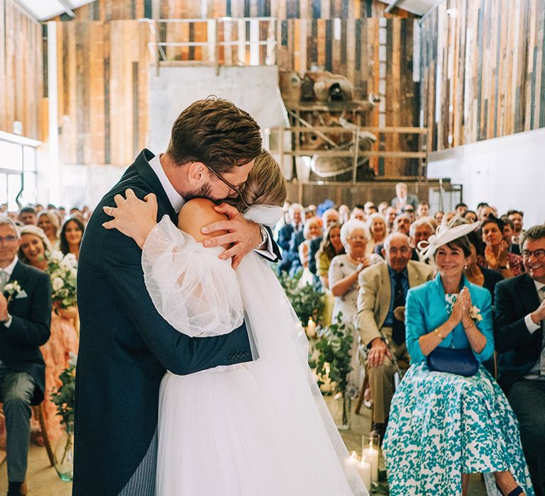 Groom in morning suit embracing the bride as they're announced as married at their non-denominational ceremony 