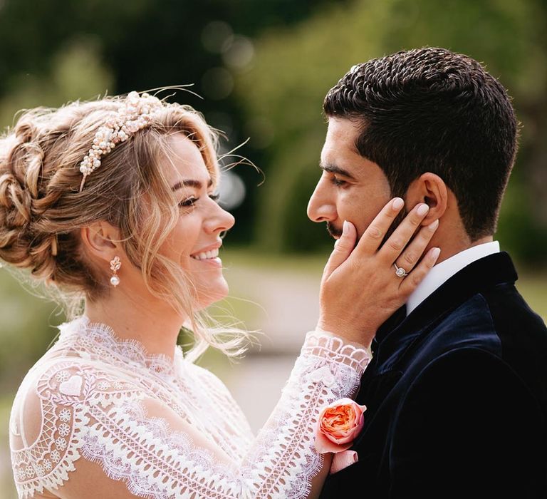 Bride in long sleeve delicate lace wedding dress with pave engagement ring and tiara with the groom in velvet suit jacket 