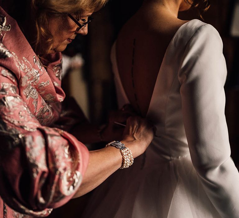 Mother of the bride in pink dress with gold embroidery with the bride in long sleeve wedding dress 