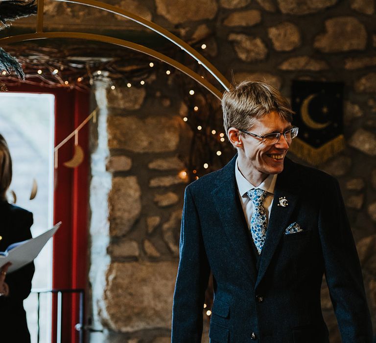 Pampas grass moon gate decorates the wedding altar with the smiling groom in a navy suit preparing to see the bride 