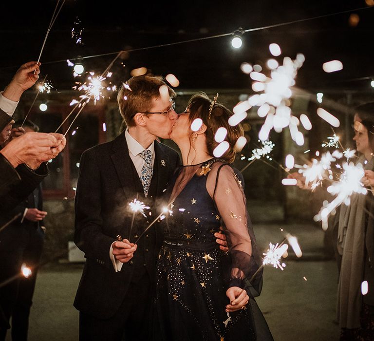 The bride and groom share a kiss during the sparkler send off at their winter wedding 