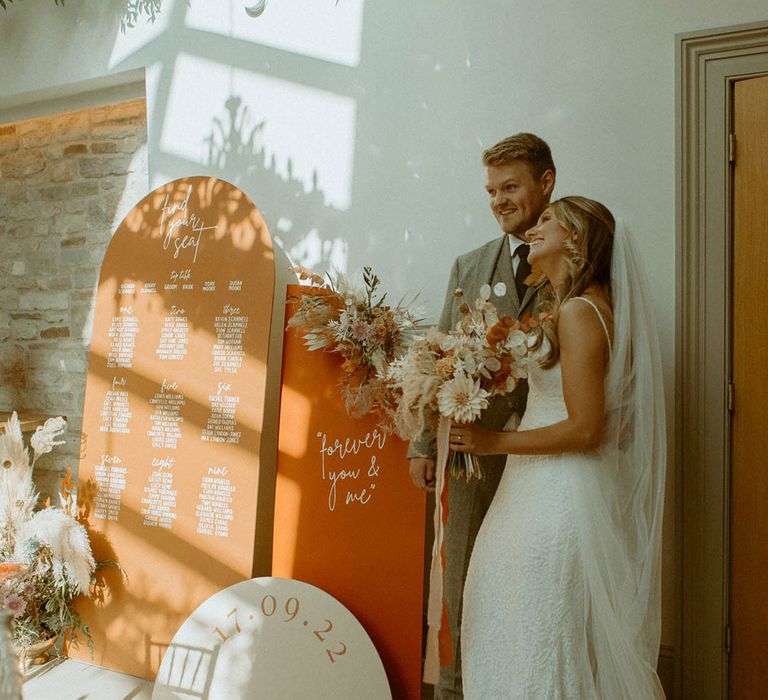 Orange boho arched wedding seating chart with pampas grass dried wedding flower arrangement with the bride and groom 