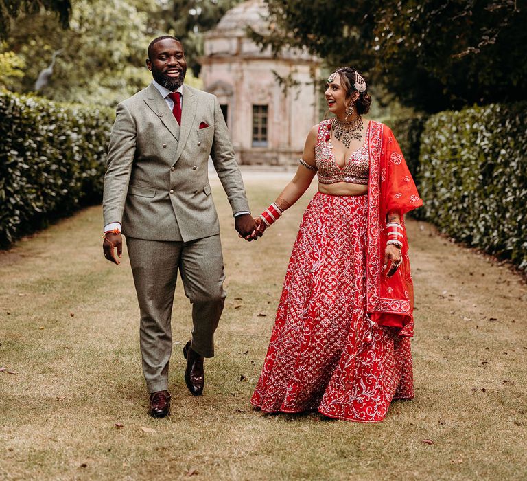 The bride and groom walk around their wedding venue together hand in hand 