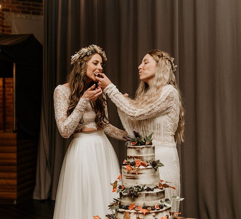 Brides eat a slice of their autumnal wedding cake together 