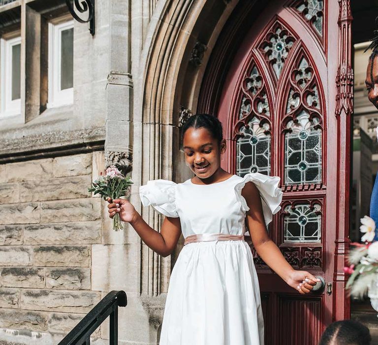 Young flower girl in a white bridesmaid dress with frilled sleeves 