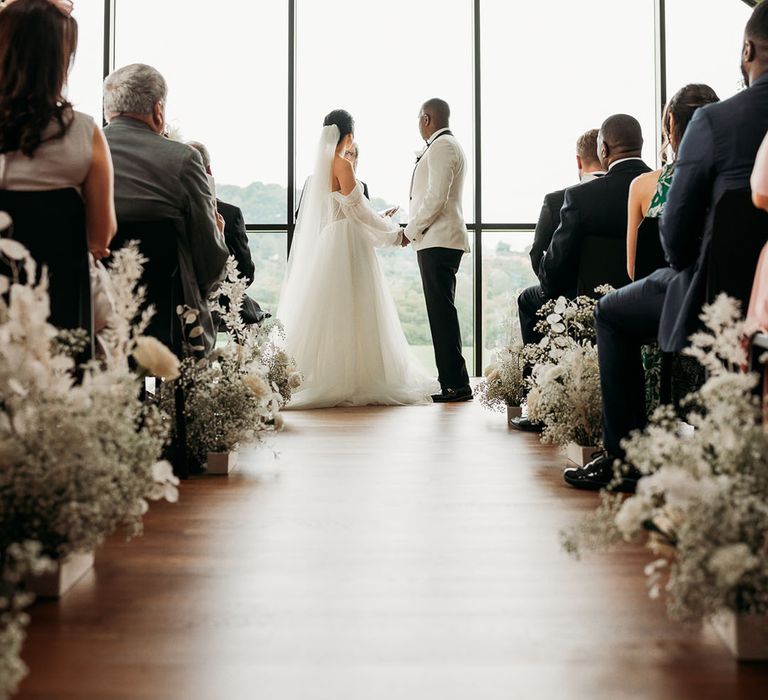 Bride in white tulle wedding dress exchanges vows with groom in black and white tuxedo at crumplebury wedding