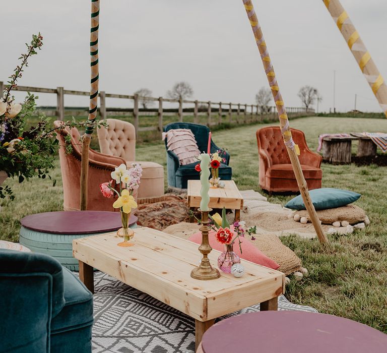 Colourful armchairs, rugs, pillows and blankets for cosy outdoor seating area at boho wedding 