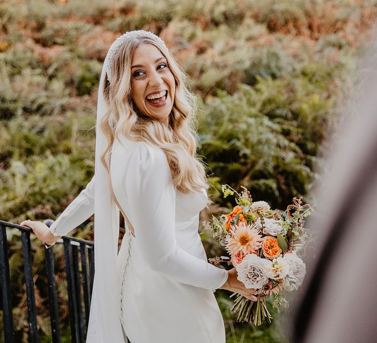 Bride in long sleeve wedding dress and veil from Sassi Holford with statement pearl headband 