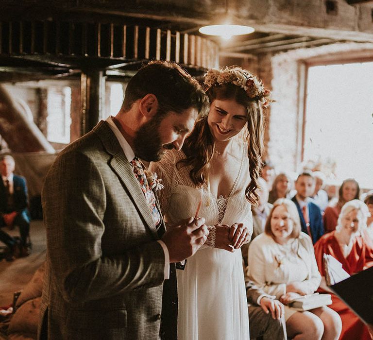 Bride and groom at their wedding ceremony at the industrial wedding venue wearing boho wedding outfits 