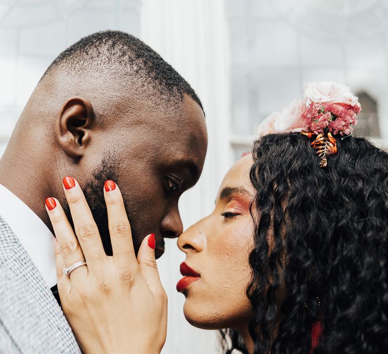 Bride embracing the groom with classic red wedding nails 