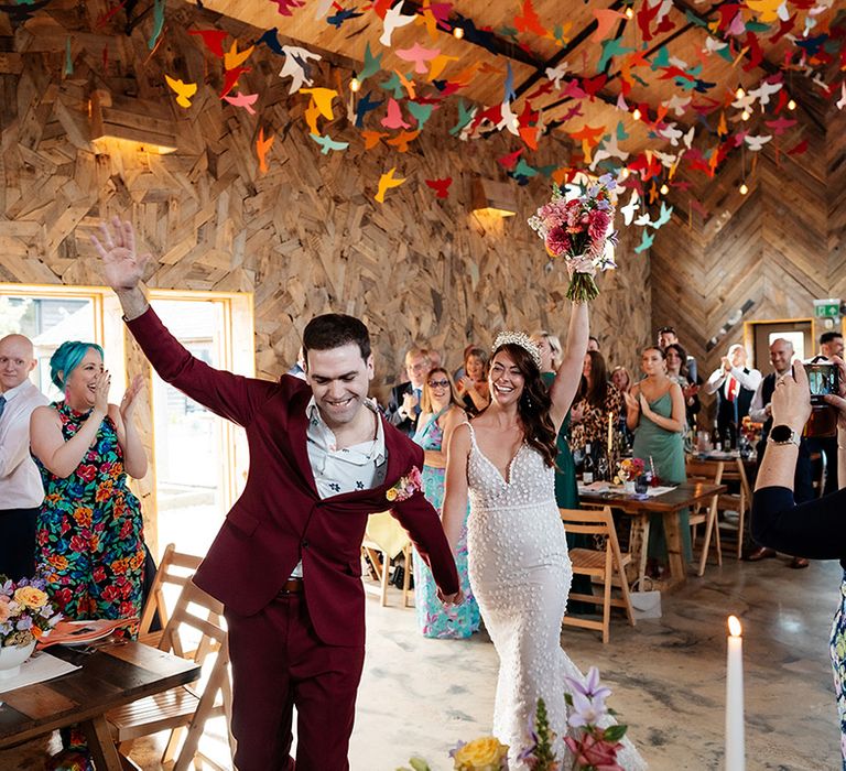 The bride and groom enter their wedding breakfast together as guests celebrate 